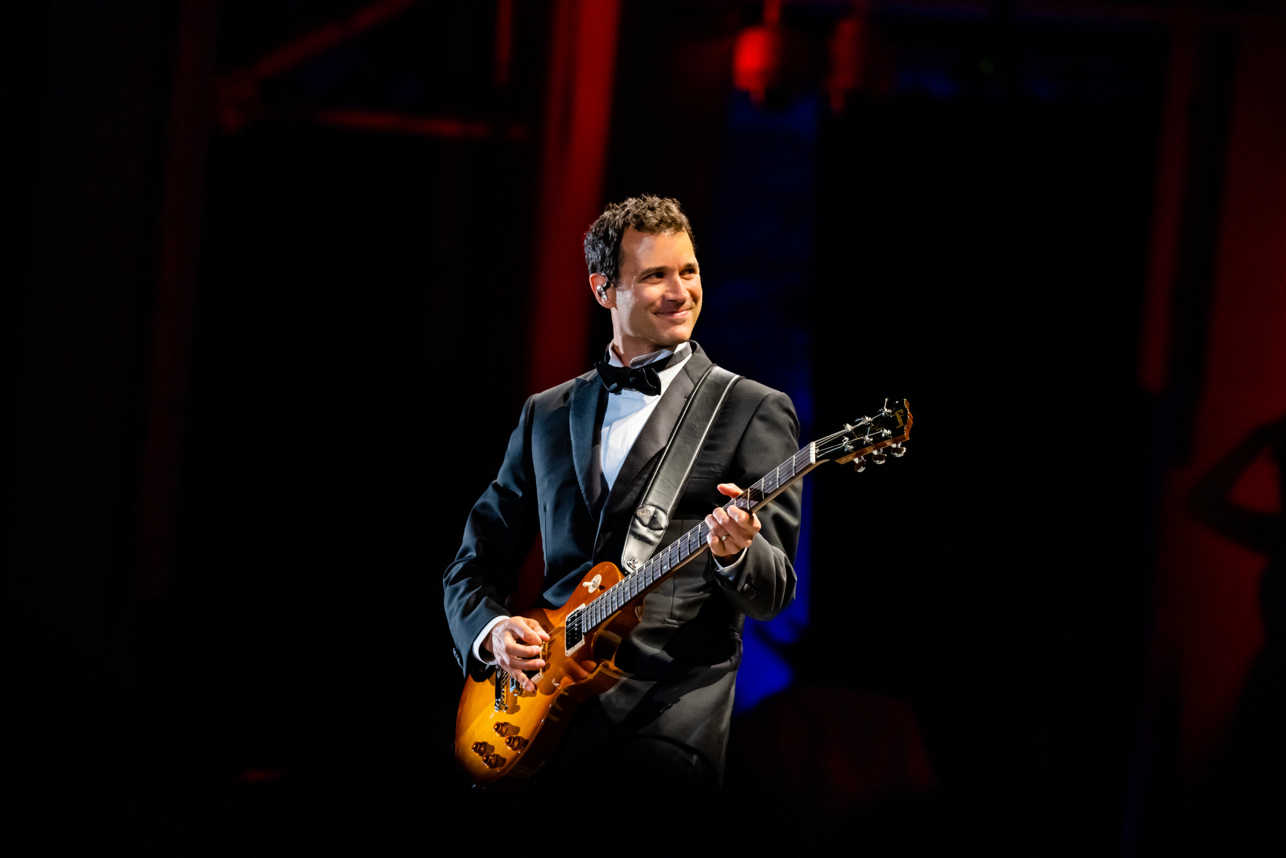 Ramin Djawadi playing the electric guitar at a live concert.